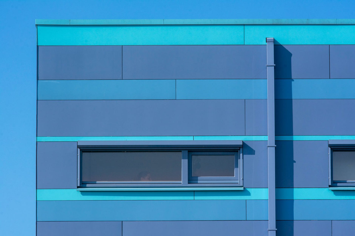Vibrant blue facade of a modern building featuring minimalistic windows and clean lines.