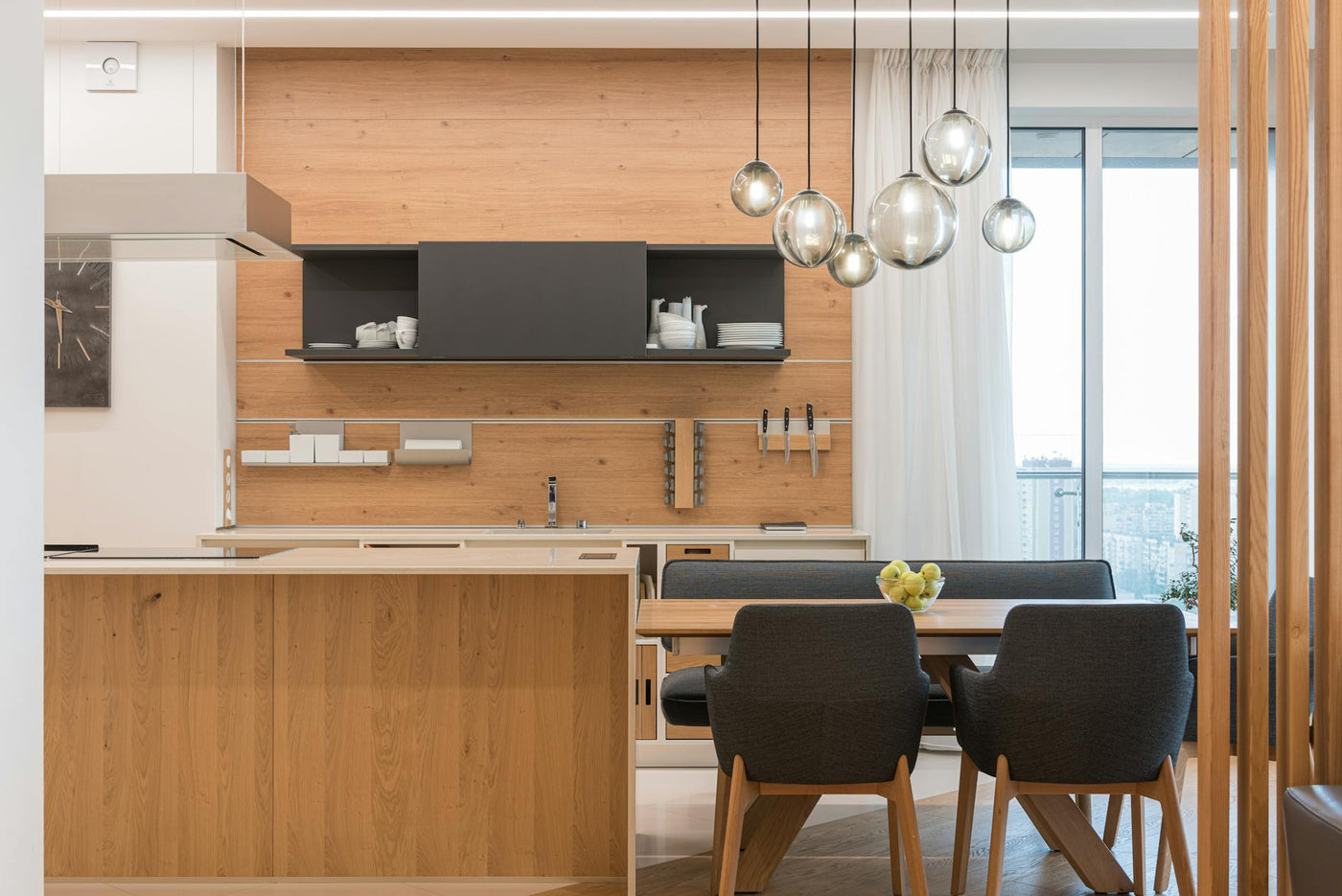 Interior of large modern kitchen with sphere shaped shiny lamps and brown furniture in daytime