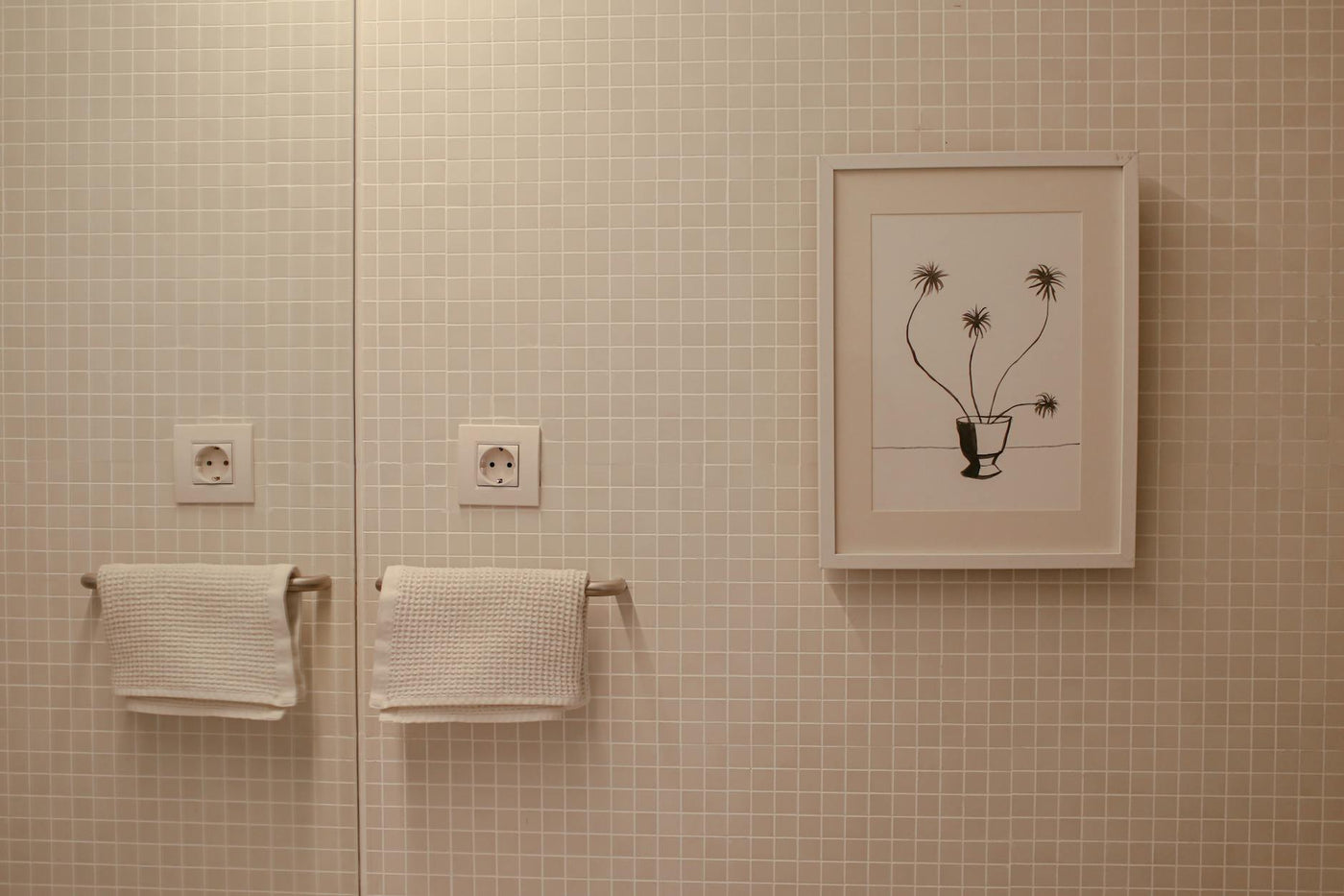 Elegant bathroom with framed art and textured towels on tiled wall.