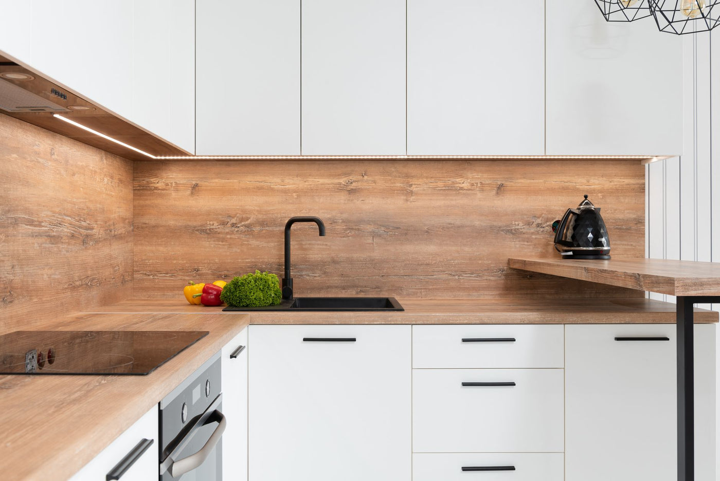 Green fresh lettuce with bell peppers placed.near sink in spacious kitchen with modern furniture and appliances