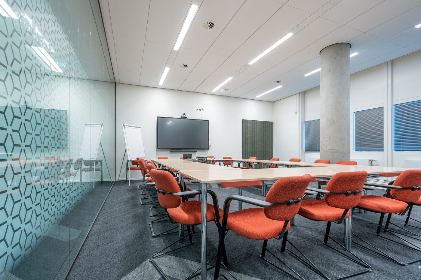Spacious and stylish conference room featuring red chairs and a glass partition.