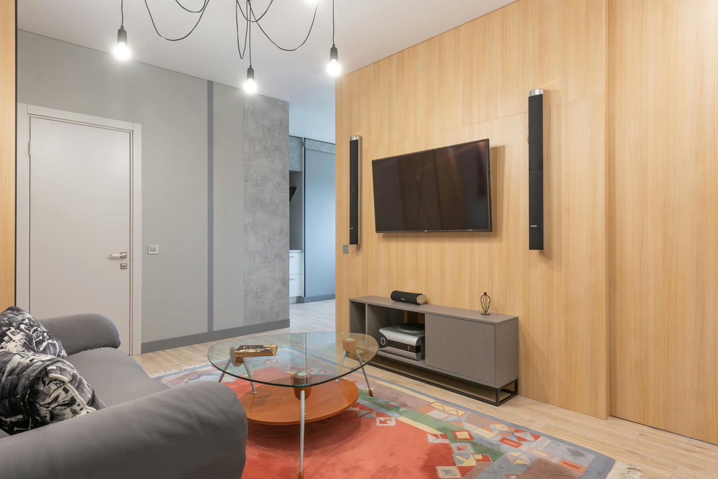 Stylish interior design of contemporary living room furnished with cozy couch and glass coffee table and decorated with creative chandelier and ornamental carpet