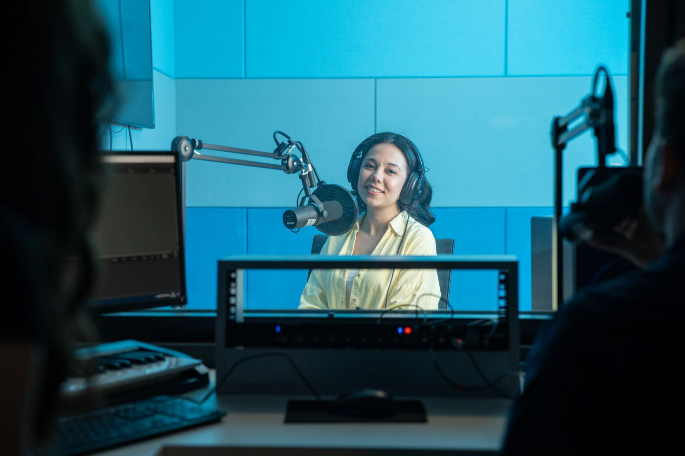 A podcast host records a show in a professional radio studio with microphones and headphones.