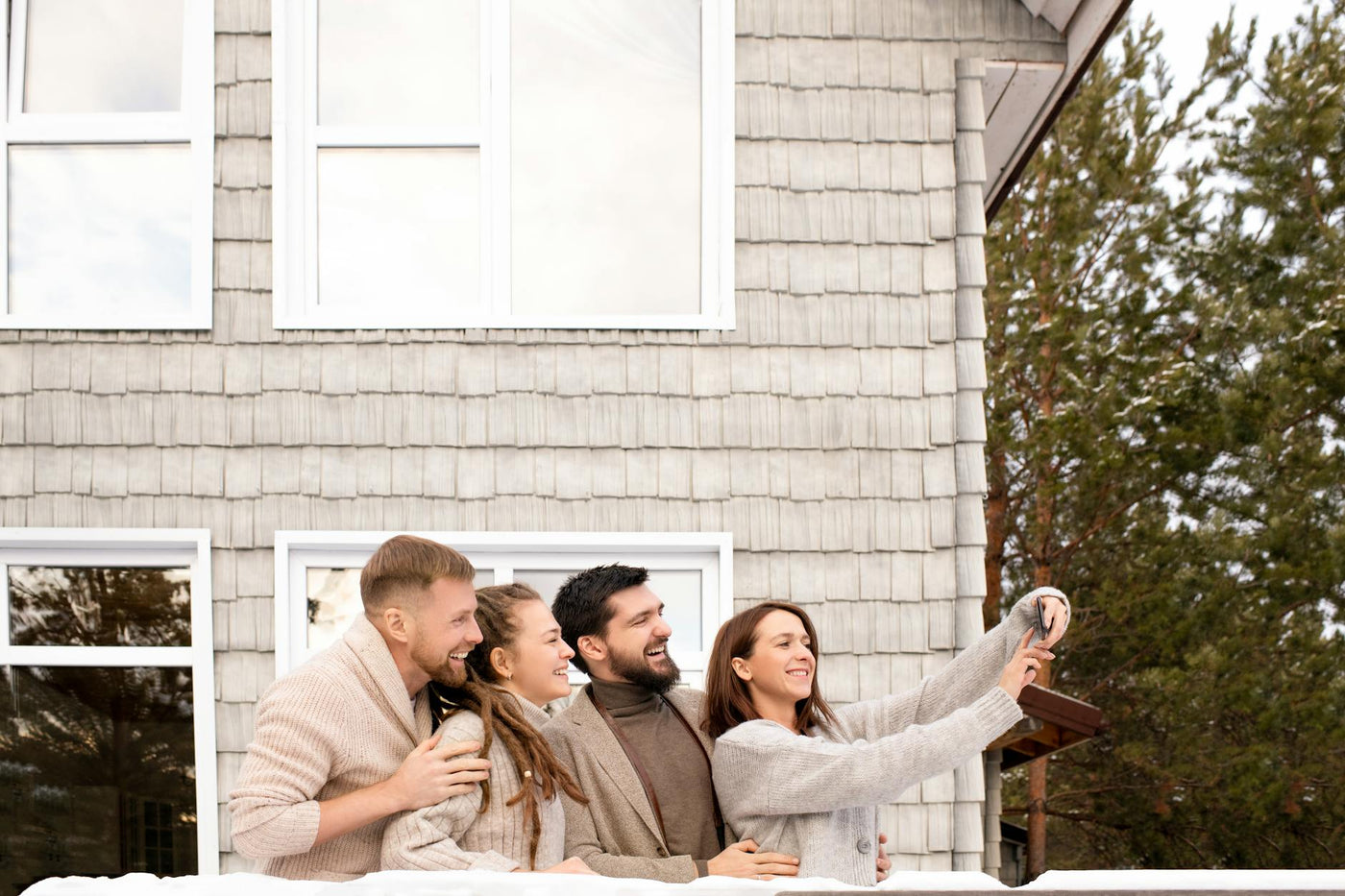 Four friends posing for a selfie in front of a house, showcasing joy and togetherness.