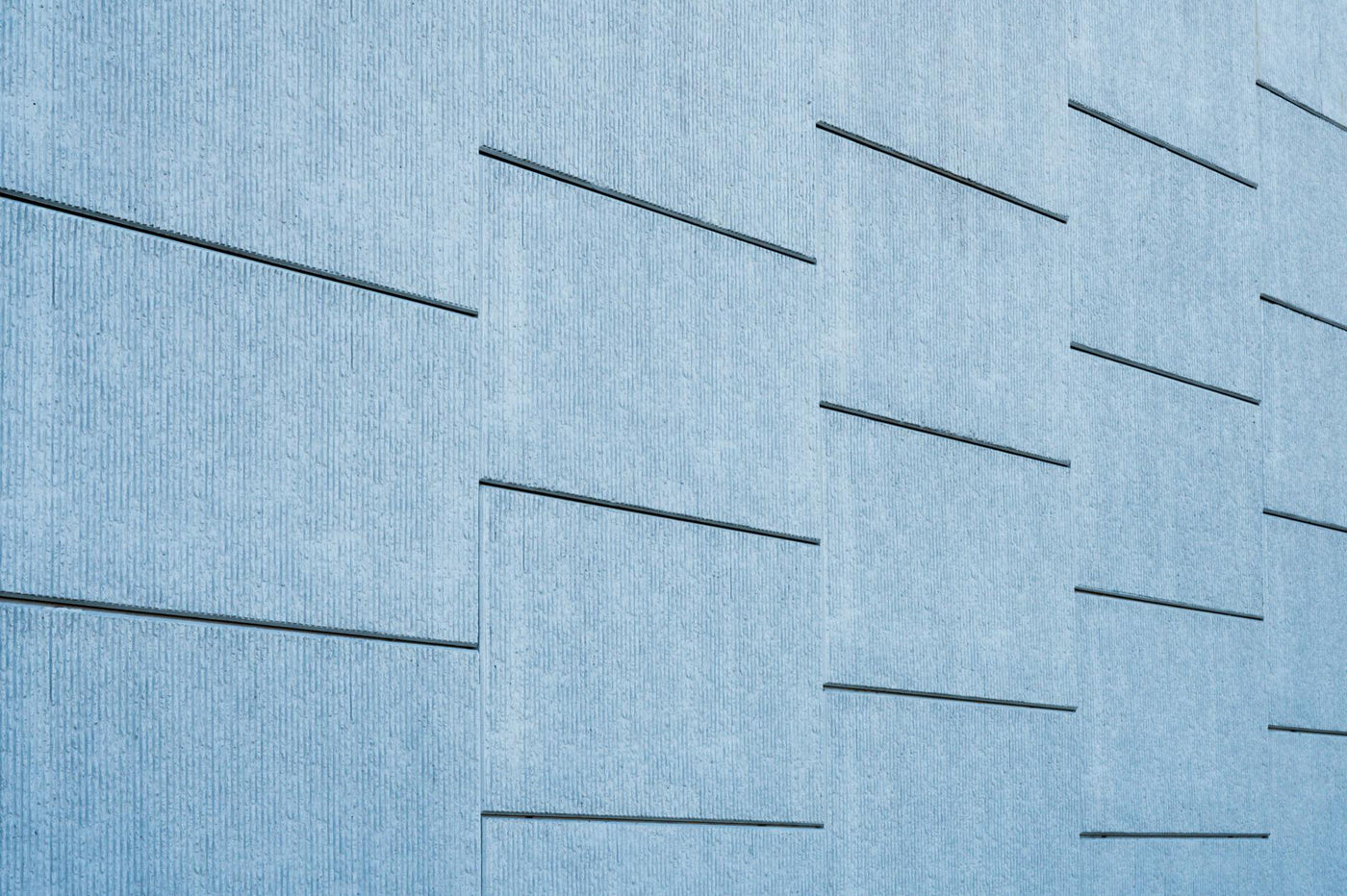 Blue tinted concrete wall featuring sleek geometric lines and modern architecture.